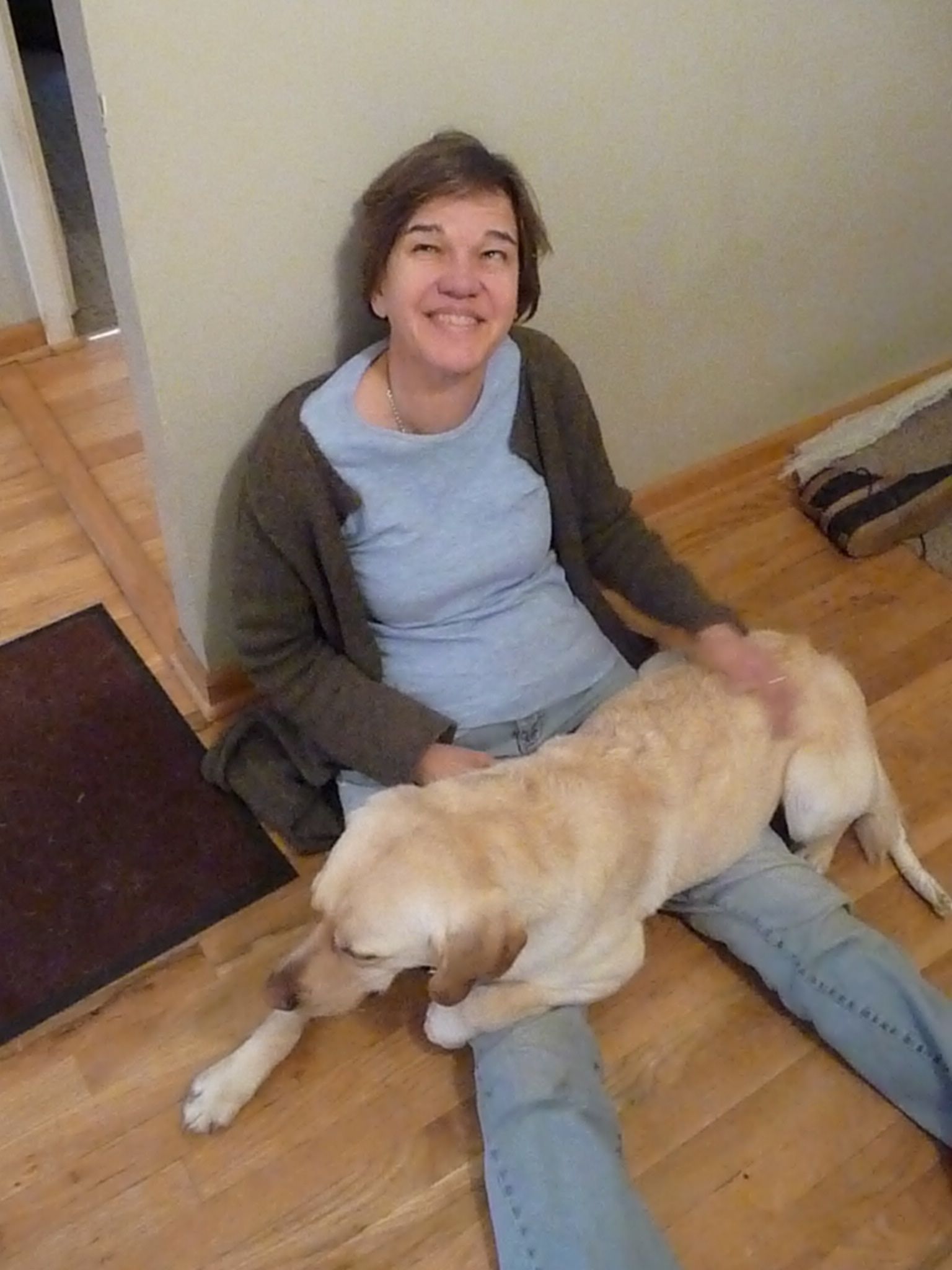 Photo of Beth's third Seeing Eye dog Harper lying across Beth's lap on the floor.