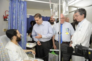 Picture of a man in the hospital being visited by several other men.