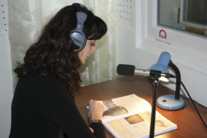 Photo of a person reading a book to be recorded on tape. 